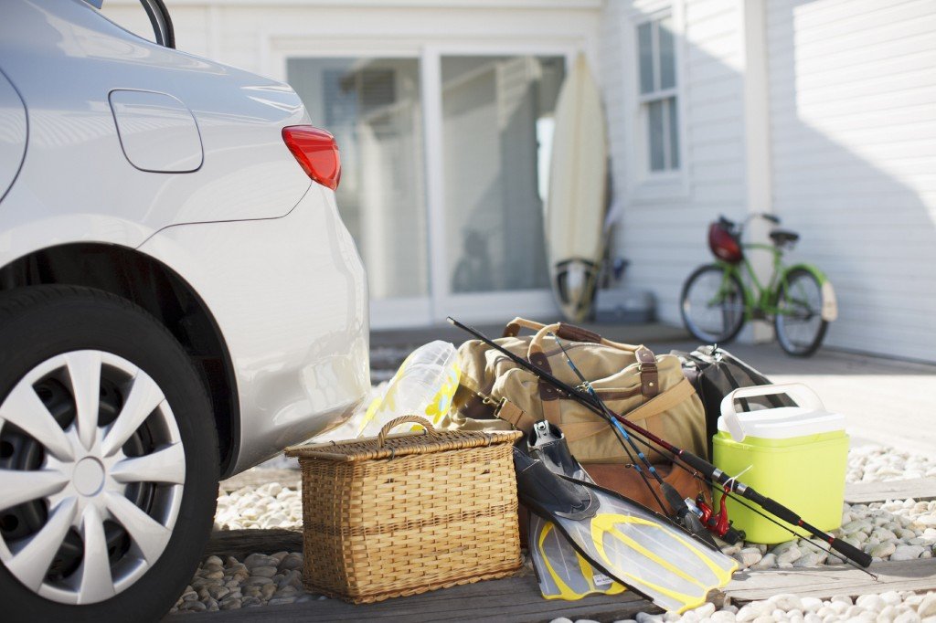 Picnic basket, fishing rod, flippers and bags outside car in driveway